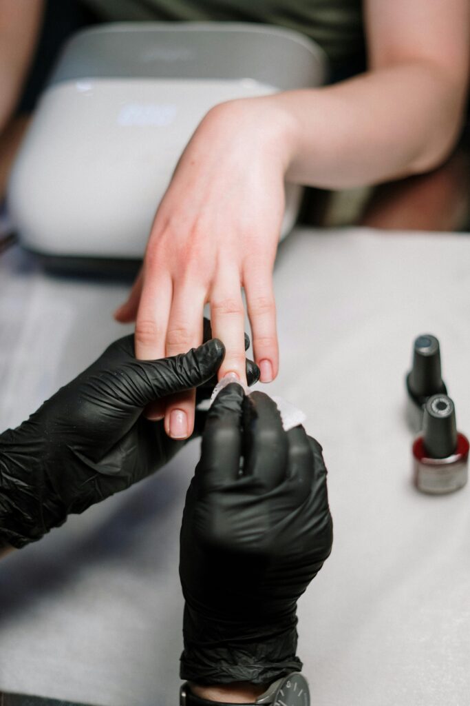 pexels-photo-3997391-3997391 Close-up of a professional manicure with gel polish and black gloves in a salon.
